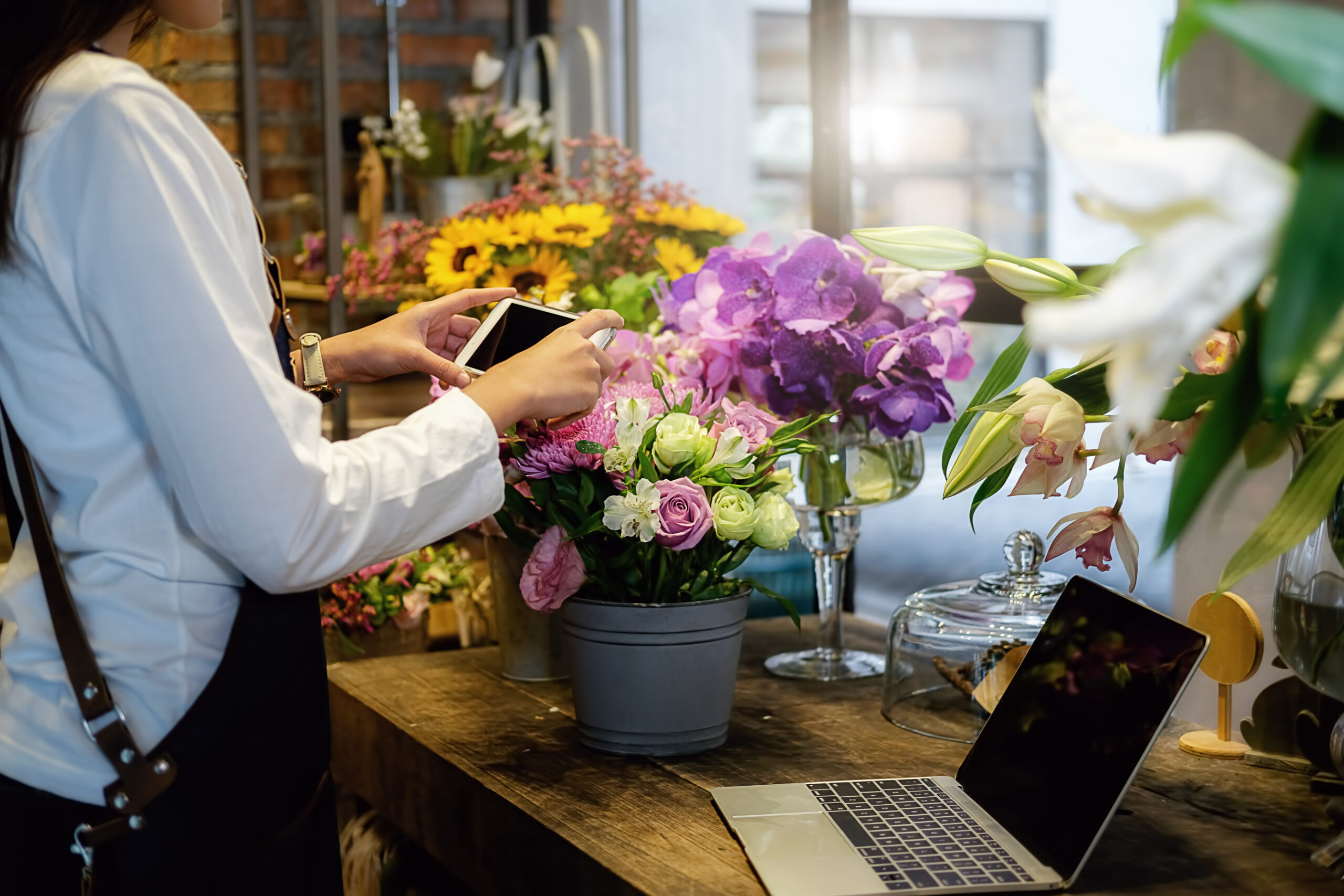 Cheerful charming young business owner flower shop store florist standing and holding flowers